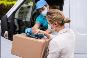 Woman receiving package from the delivery man on a van photo