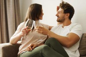 pareja feliz bebiendo vino y relajándose en casa foto