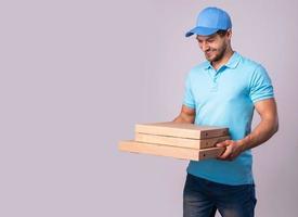 Young delivery man is holding boxes with a delicious pizza photo