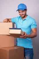 Happy delivery man during work with a packages in a cardboard boxes photo