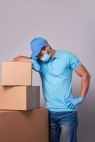 Young delivery man is wearing prevention mask and gloves with a cardboard boxes photo