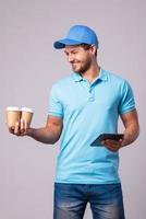 Delivery man is using tablet pc for navigation and brings two cups of coffee photo