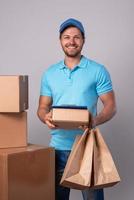 Happy delivery man during work with a packages in a cardboard boxes photo