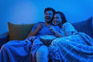 Young and happy couple watching comedy TV show photo