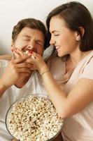 pareja feliz comiendo palomitas de maíz y viendo películas en casa foto