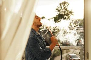Handsome man smoking hookah on a balcony photo