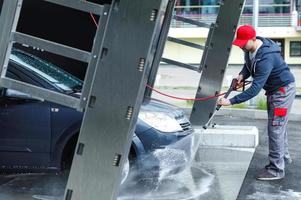 Car wash worker is washing client's car photo