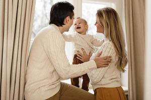 familia joven y feliz de pie junto a la ventana foto