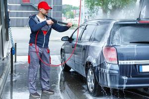 trabajador de lavado de autos está lavando el auto del cliente foto