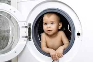 Curious baby boy sitting inside the washing machine photo