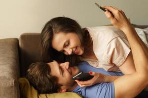 Young couple lying on a sofa and using smartphones photo