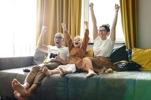 familia feliz está jugando consola de videojuegos en casa foto