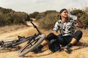 Bike rider relaxing after downhill race on bicycle in a mountains photo