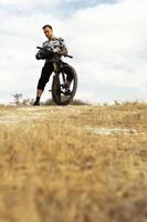 Professional downhill rider with his bicycle on top of mountain photo