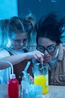 Teacher and little girl during chemistry lesson mixing chemicals in a laboratory photo