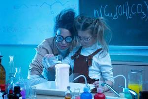 profesor y niña durante la lección de química mezclando productos químicos en un laboratorio foto