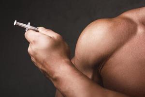 Muscular man with a syringe in his hand photo