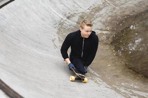 Young handicapped guy with a longboard in a skatepark photo