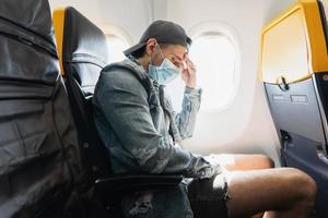 hombre con máscara de prevención durante un vuelo dentro de un avión foto