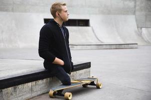 Motivated handicapped guy with a longboard in the skatepark photo