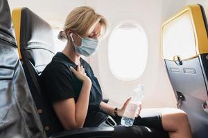 Woman wearing prevention mask during a flight inside an airplane photo