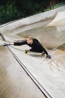 Motivated handicapped guy with a longboard in the skatepark photo