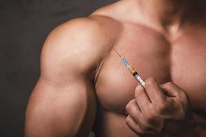 Muscular man with a syringe in his hand photo