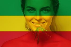 hermosa mujer con una hoja de cannabis en colores de la bandera rastafari foto