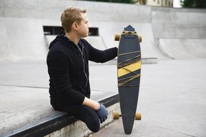 Young handicapped guy with a longboard in a skatepark photo