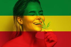hermosa mujer con una hoja de cannabis en colores de la bandera rastafari foto