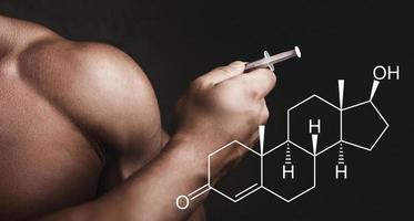 Muscular man with a syringe in his hand and testosterone formula. photo