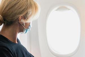 Woman wearing prevention mask during a flight inside an airplane photo