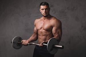 Massive brutal bodybuilder doing exercises with barbell photo