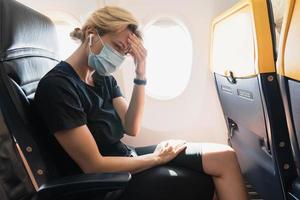 mujer con máscara de prevención durante un vuelo dentro de un avión