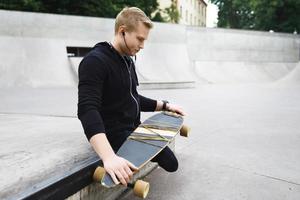 Young handicapped guy with a longboard in a skatepark photo