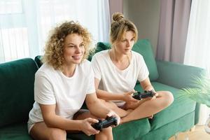 Two beautiful girls playing video game console in  living room photo