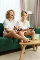 dos hermosas chicas jugando consola de videojuegos en la sala de estar foto