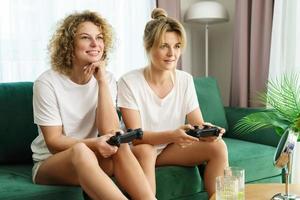 Two beautiful girls playing video game console in  living room photo