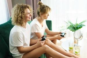 Two beautiful girls playing video game console in  living room photo