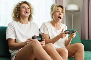 Two beautiful girls playing video game console in a living room photo