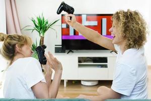 dos hermosas chicas jugando consola de videojuegos en una sala de estar foto