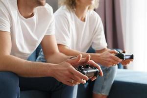 una pareja con gamepads está jugando una consola de videojuegos foto