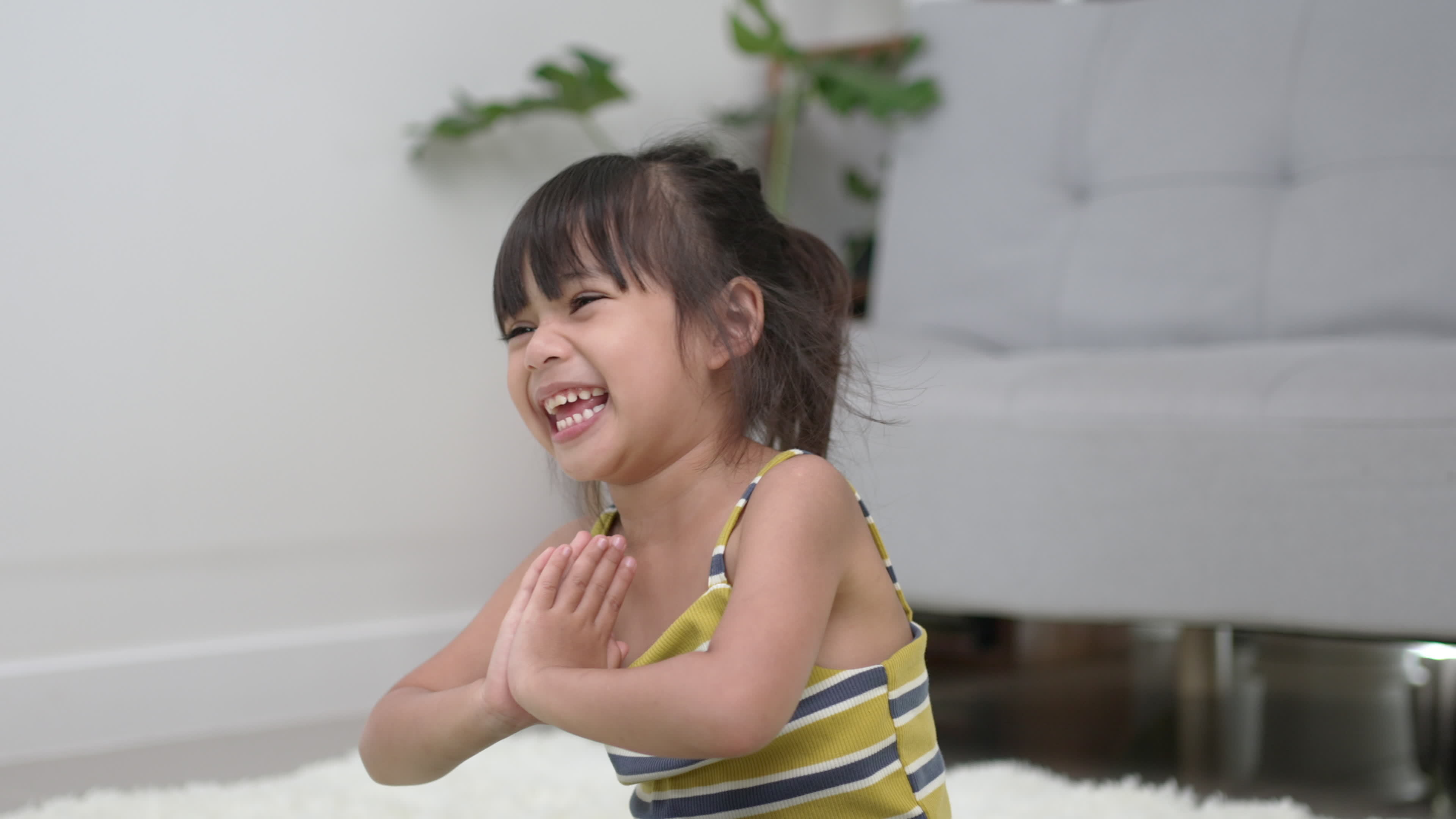 Funny Little Asian girl sitting on carpet in meditation pose at home,  closed her eye and laughing when open eyes 16238253 Stock Video at Vecteezy