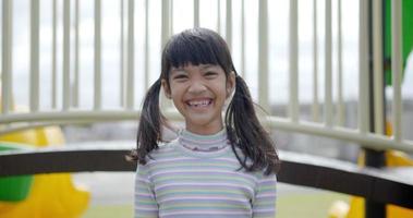 Porträt schönes asiatisches Mädchen, das in die Kamera schaut und glücklich auf dem Spielplatz lacht
