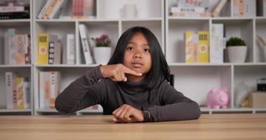 portret van Aziatisch leerling meisje kort haar- richten en op zoek Bij polshorloge terwijl zittend Bij bureau in klas. onderwijs en tijd uit concept. video