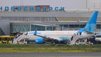 novosibirsk, federación rusa 15 de julio de 2022 - los pasajeros bajan del avión pobeda airlines en el aeropuerto de tolmachevo. la gente baja las escaleras desde el avión hasta la plataforma del aeropuerto. video