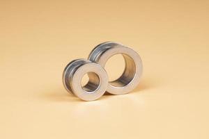 silver tunnel piercing  accessory close up on beige background photo