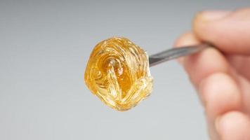 yellow resin extract on dab stick tool closeup, gold  wax smear for stoner smoke photo