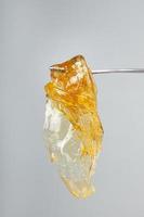 yellow gold cannabis extract wax concentrate dripping from the dabbing tool closeup photo