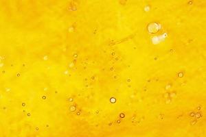 strong extract of gold cannabis wax with high thc close up, bubble shatter texture photo